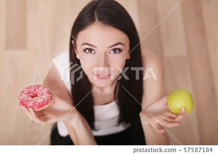 Diet. Woman Measuring Body Weight On Weighing Scale Holding Donut and apple. Sweets Are Unhealthy 57587184