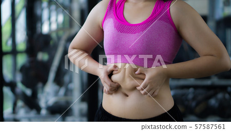 Close up woman holding excessive fat belly. Woman overweight abdomen. Woman diet lifestyle concept reduce belly and shape up healthy stomach muscle. Weight loss, slim body, healthy lifestyle concept. Close up woman holding excessive fat belly. Woman overweight abdomen. Woman diet lifestyle concept reduce belly and shape up healthy stomach muscle. Weight loss, slim body, healthy lifestyle concept. 57587561