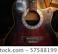 Acoustic guitar resting against a wooden background  57588199