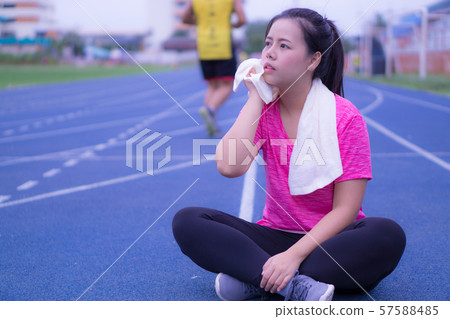 Asian beauty woman wiping sweat with towel on running track. 57588485
