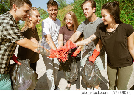 Group of volunteers tidying up rubbish on beach 57589054