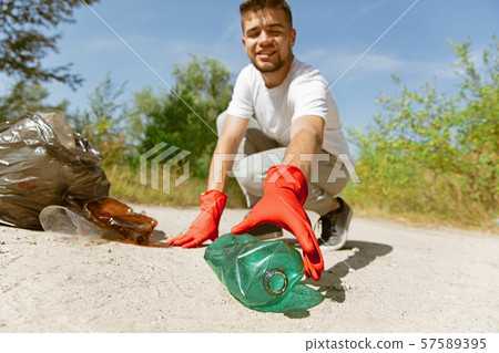 Volunteer tidying up rubbish on beach Volunteer tidying up rubbish on beach 57589395