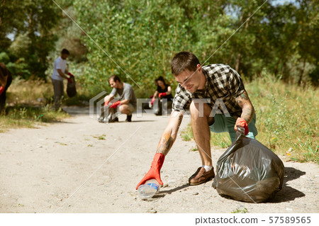 Group of volunteers tidying up rubbish on beach Group of volunteers tidying up rubbish on beach 57589565