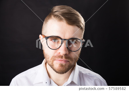 Portrait of young serious bearded man and in glasses over the black background 57589582
