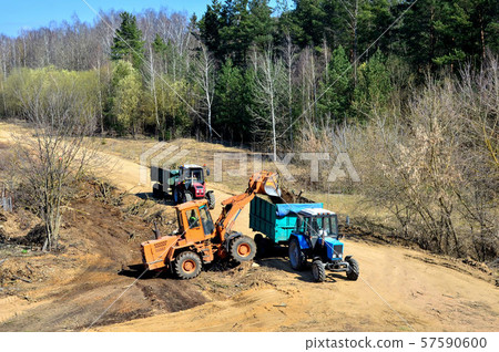 A front loader loads waste into a tractor when building a road in a forested area 57590600