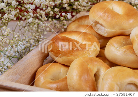 Fresh homemade bagels in tray with flowers. Fresh homemade bagels in tray with flowers. 57591407