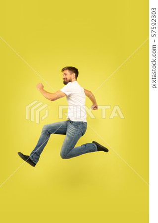 Full length portrait of happy jumping man on yellow background Full length portrait of happy jumping man on yellow background 57592303