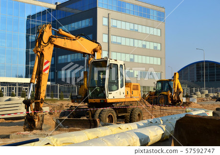 Heavy construction equipment and earthmoving excavators working on a construction site in the city. Heavy construction equipment and earthmoving excavators working on a construction site in the city. 57592747