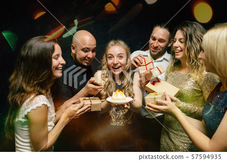 Friends congratulating young woman at her birthday Friends congratulating young woman at her birthday 57594935