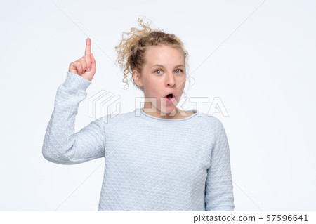 Curly girl looking excited holding her mouth opened pointing up having idea. 57596641