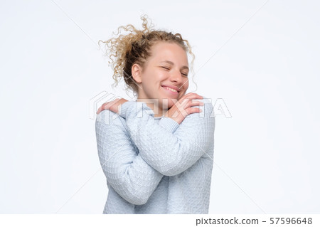 Attractive tender young woman standing and hugging herself Attractive tender young woman standing and hugging herself 57596648
