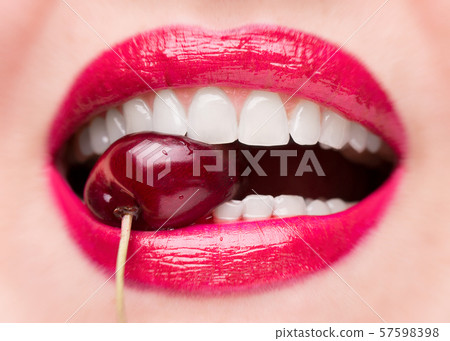 The girl bites a ripe cherry. Cherry in mouth 57598398