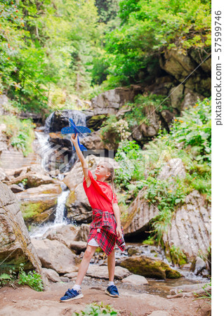 Happy little girl with toy airplane in hands in mountains 57599746