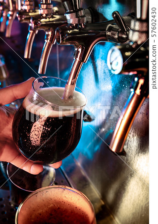 Hand of bartender pouring a large ale, porter, stout beer in tap Hand of bartender pouring a large ale, porter, stout beer in tap 57602430