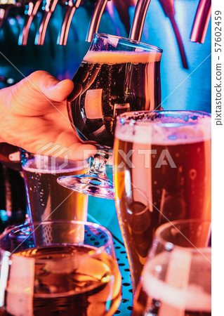 Hand of bartender pouring a large lager beer in tap 57602459