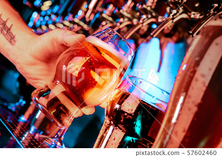 Hand of bartender pouring a large lager beer in tap 57602460
