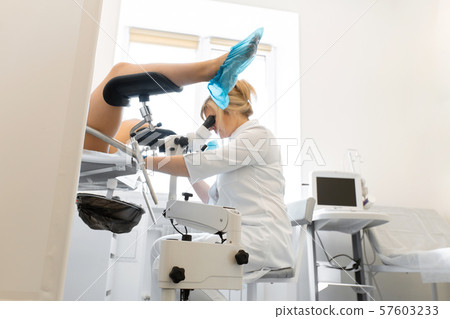 A gynecologist examines a patient on a 57603233