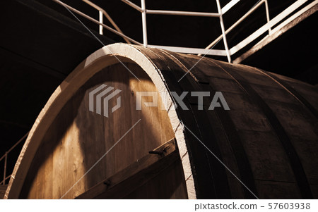 Old brown wooden barrel in dark winery Old brown wooden barrel in dark winery 57603938