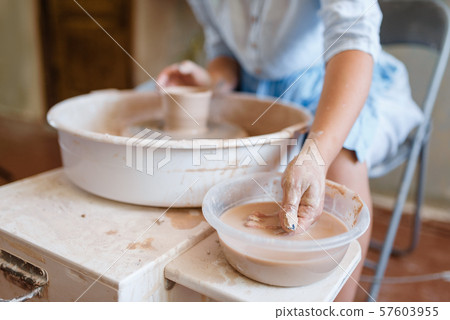 Female master making a pot on pottery wheel 57603955