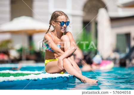 Beautiful little girl having fun near an outdoor pool Beautiful little girl having fun near an outdoor pool 57604058