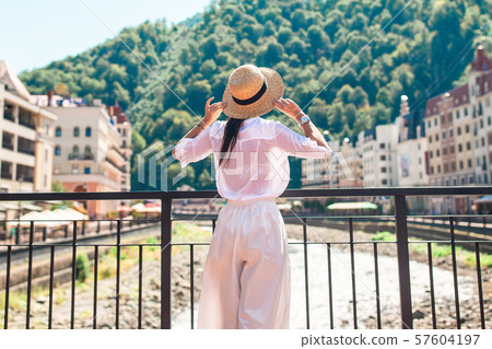 Happy girl at hat on the embankment of a mountain river in a European city. 57604197