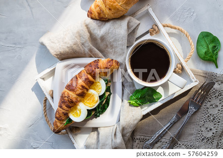Coffee and croissant with egg and sauteed spinach Coffee and croissant with egg and sauteed spinach 57604259