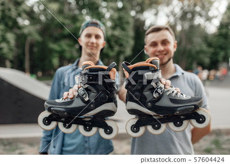 Roller skating, two skaters holds skates in hands 57604424