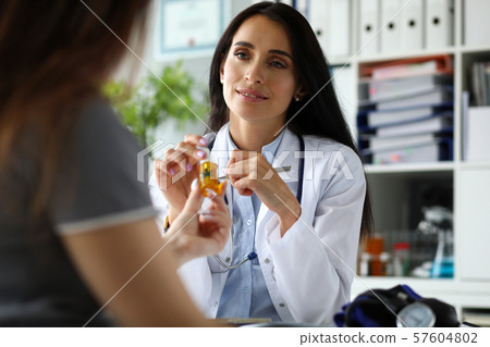 Female GP giving patient dropper jar of cannabis concentrate oil 57604802
