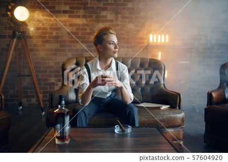 Woman in shirt and trousers with whiskey and cigar 57604920