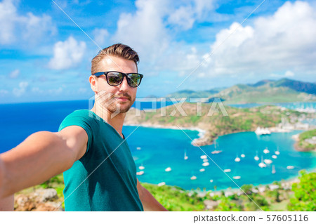 Young man taking selfie with view of English Harbor from Shirley Heights, Antigua, paradise bay at Young man taking selfie with view of English Harbor from Shirley Heights, Antigua, paradise bay at 57605116