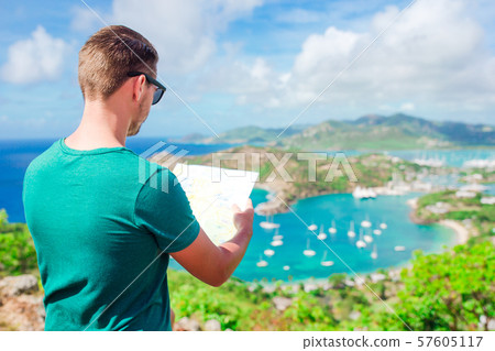 Young tourist man with map background of English Harbor from Shirley Heights, Antigua, paradise bay Young tourist man with map background of English Harbor from Shirley Heights, Antigua, paradise bay 57605117