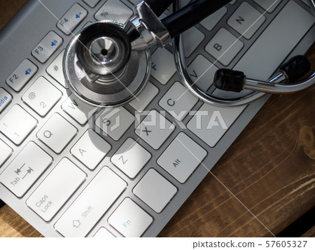 Stethoscope head lying on silver keyboard closeup 57605327
