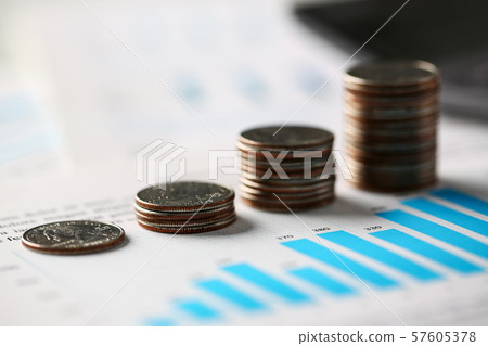 Pile of silver coins stand at financial graph papers 57605378