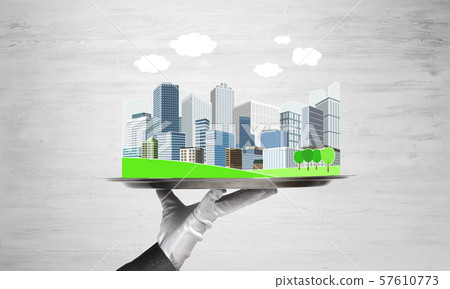 Hand holding metal tray with modern city model against wooden background 57610773
