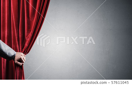 Concrete wall behind drapery curtain and hand opening it Concrete wall behind drapery curtain and hand opening it 57611045