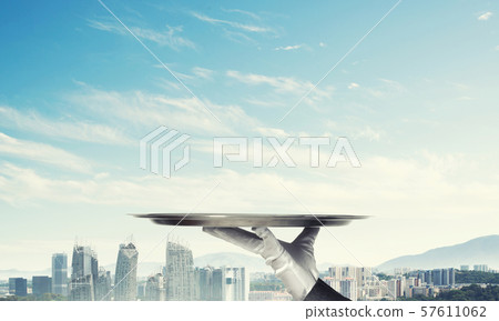 Hand presenting metal empty tray and modern city landscape at background Hand presenting metal empty tray and modern city landscape at background 57611062