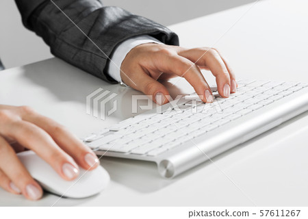 Closeup of businesswoman hand typing on keyboard with mouse on wood table 57611267