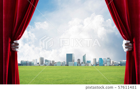 Green meadow behind red curtain and hand holding it Green meadow behind red curtain and hand holding it 57611481