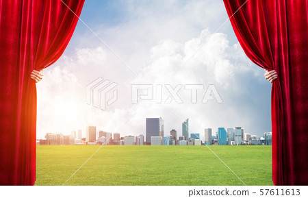 Green meadow behind red curtain and hand holding it Green meadow behind red curtain and hand holding it 57611613