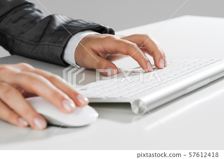 Closeup of businesswoman hand typing on keyboard with mouse on wood table Closeup of businesswoman hand typing on keyboard with mouse on wood table 57612418