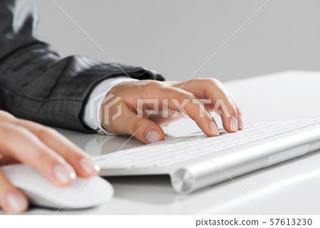 Closeup of businesswoman hand typing on keyboard with mouse on wood table 57613230