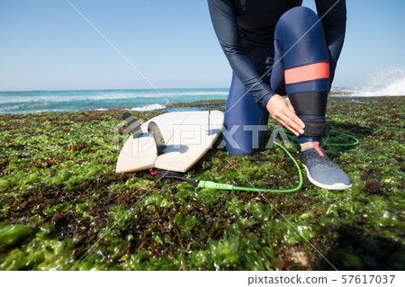 woman surfer tying leg leash with surfboard on 57617037