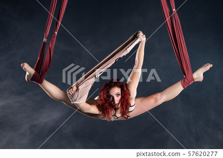 Female athletic, sexy and flexible aerial circus artist with redhead dancing in the air on the silk Female athletic, sexy and flexible aerial circus artist with redhead dancing in the air on the silk 57620277