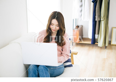 Young woman using computer while sitting on couch Young woman using computer while sitting on couch 57620867