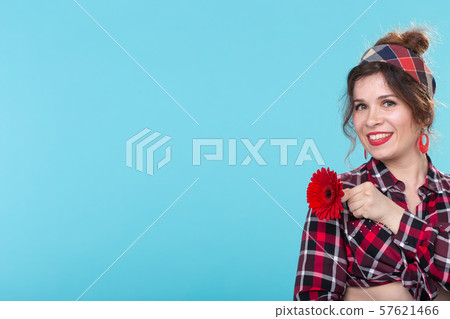Charming smiling young positive woman in a plaid shirt holding bright yellow flowers in her hands 57621466
