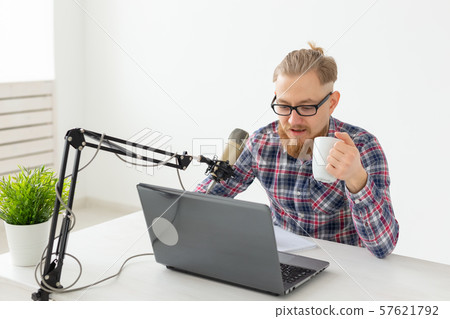 Radio, DJ, blogging and people concept - Smiling man sitting in front of microphone, host at radio Radio, DJ, blogging and people concept - Smiling man sitting in front of microphone, host at radio 57621792