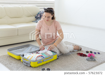 Summer holidays, voyage and traveler concept - Young beautiful woman packs a suitcase on a summer 57623872