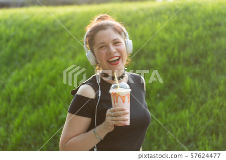 Portrait of a positive young pretty girl in punk clothes and glasses with a milkshake in her hands 57624477