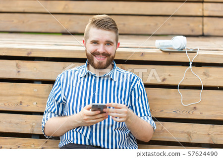 Happy young male hipster student with a mustache and beard writing sms message to his friends 57624490
