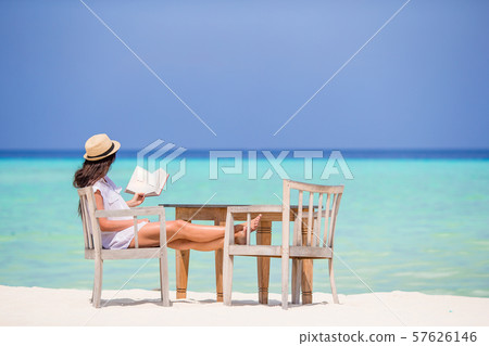 Young woman reading at outdoor beach cafe 57626146